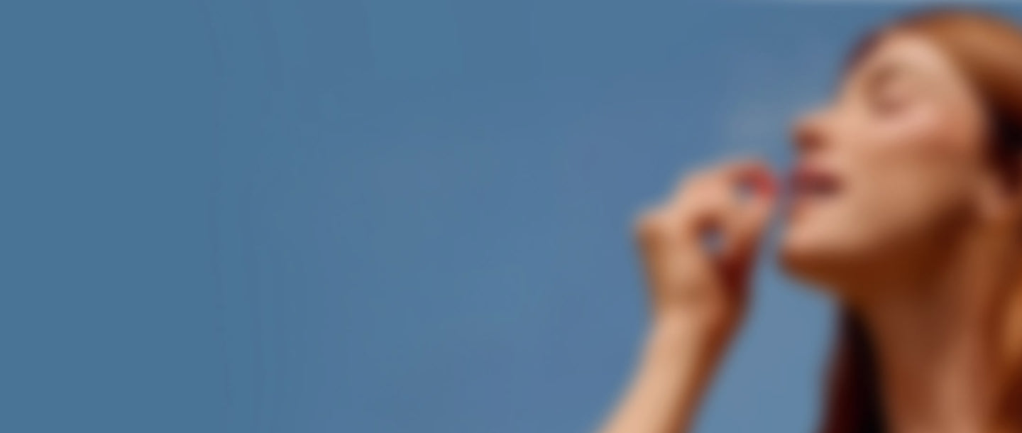 A woman taking a Needed prenatal multivitamin against a blue sky